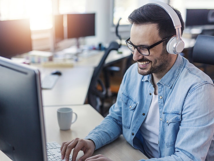 Photo of a male engineer in front of his computer workstation with headphones on